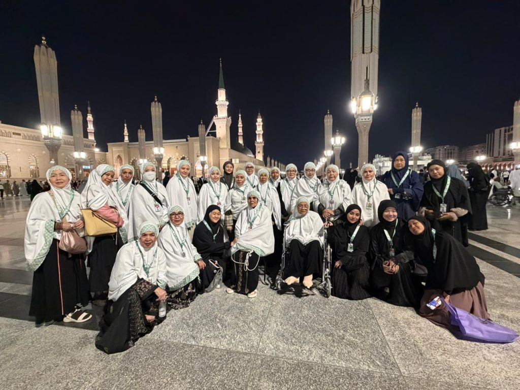 Rombongan jemaah wanita Safari Suci berfoto dengan nyaman di pelataran Masjid Nabawi pada malam hari, menginspirasi pentingnya persiapan umrah wanita yang praktis dan matang.