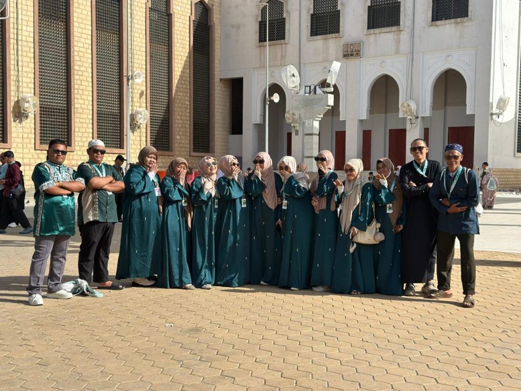 Sekelompok jemaah Umrah Safari Suci berpose bersama di pelataran masjid di Madinah, menunjukkan keberangkatan tepat waktu dan menjawab pertanyaan tentang 'Umrah Nunggu Berapa Lama' dengan kepastian.