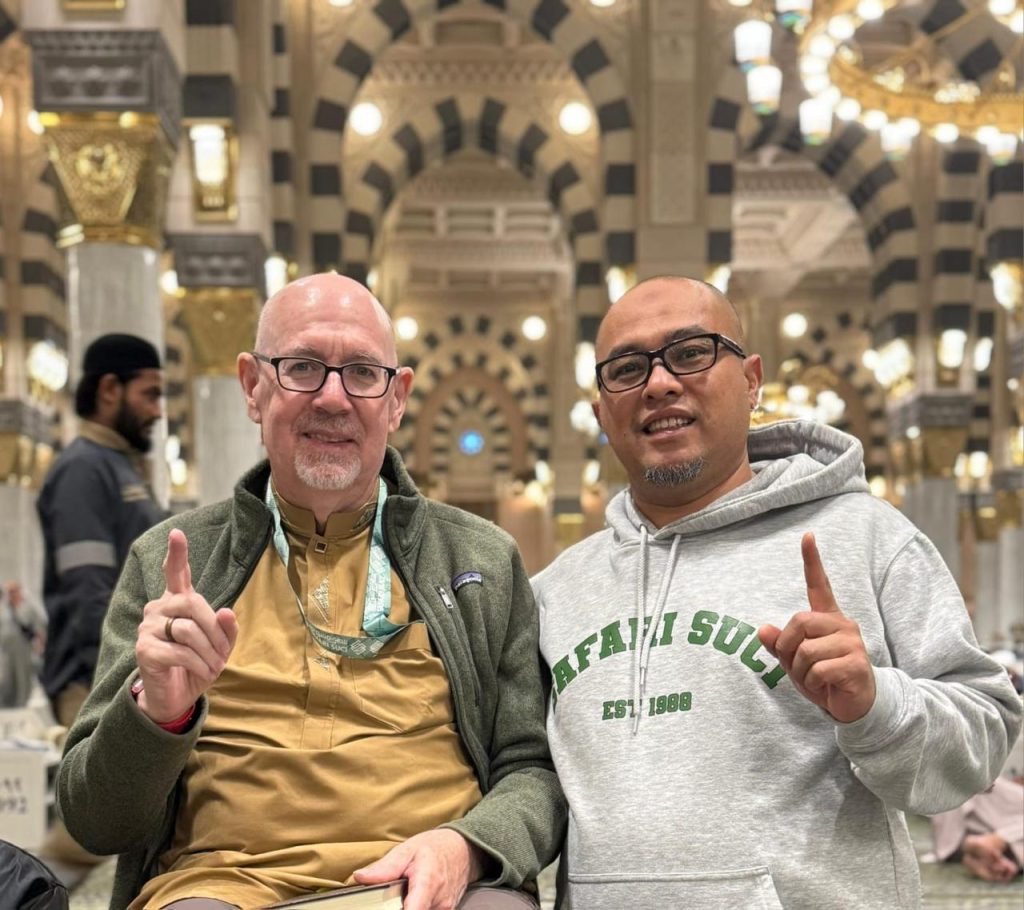 Dua pria profesional mapan berkacamata dengan penampilan botak rapi setelah tahallul di Masjid Nabawi, Madinah, membuktikan bahwa keraguan 'Umrah wajib botak' tidak mengganggu citra profesional mereka sepulang ibadah bersama Safari Suci.