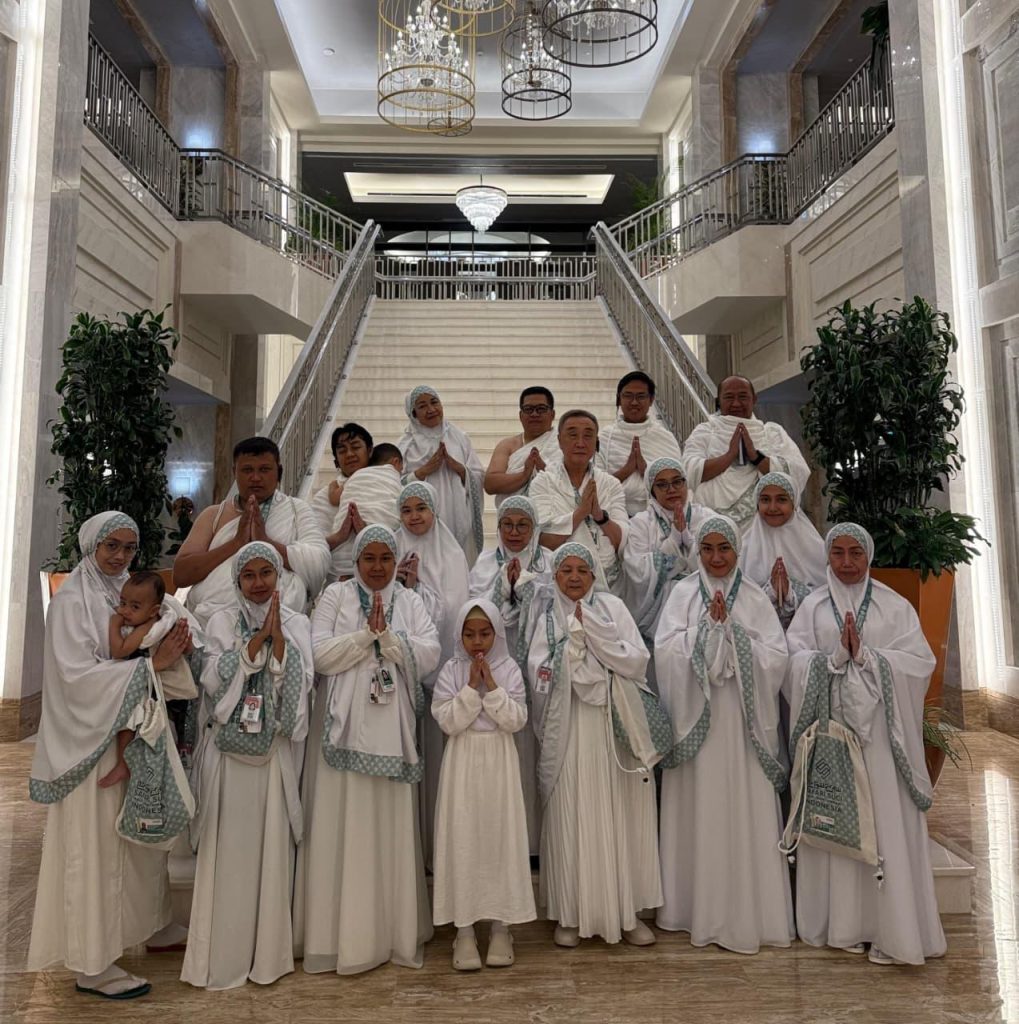Rombongan jemaah Safari Suci berpakaian ihram berfoto bersama di tangga hotel saat persiapan Umrah atau Umroh